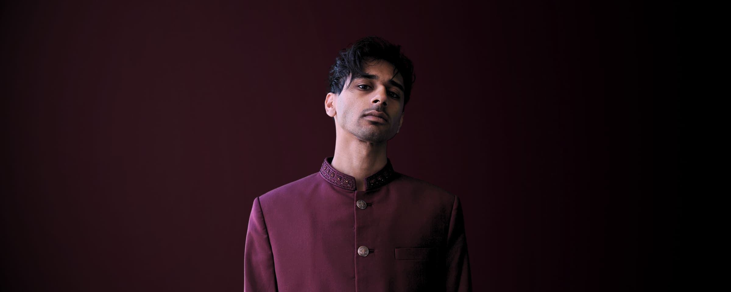 Editorial cinematic portrait of Bisaria in a burgundy bandhgala